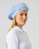 Daily Sports Hudson Beret in Light Blue – women's ribbed knit golf beret with metallic logo pin, side view styled with white golf pol