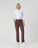 A woman modeling a white long-sleeve polo shirt and brown straight-leg trousers against a light gray studio background.