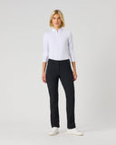 A woman modeling a white long-sleeve polo shirt and black trousers against a light gray studio background.