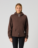 A woman modeling a dark brown hooded zip-up jacket with front flap pockets, paired with black leggings, against a light gray studio background.