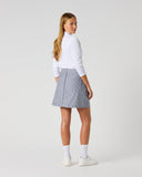 Daily Sports Stripe Dark Navy Skort in dark navy and white vertical pinstripe – women's pleated A-line golf skort showing pleated back panel and flared hem, three-quarter back view on model styled with white long sleeve polo