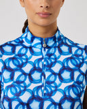 Woman wearing a sleeveless top with blue circular pattern on a light gray background