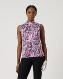 Woman wearing a sleeveless patterned top and black pants on a white background