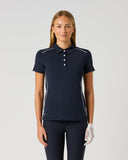 Daily Sports Dark Navy Piping Short Sleeve Polo in deep navy – women's short sleeve golf polo with white contrast piping along shoulders and side seams, classic collar and white button placket, front view on model styled with navy trousers and golf glove