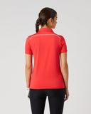 A woman viewed from the back wearing a bright red short-sleeve athletic polo shirt with thin white piping details across the shoulders, paired with black leggings, against a solid light gray background.