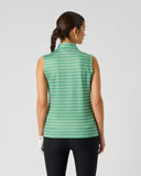A woman shown from the back wearing a sleeveless high-neck top with a green and white geometric pattern, paired with black pants, against a light gray studio background.
