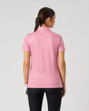 A woman viewed from the back wearing a short-sleeve pink and white gingham check shirt and black pants, standing against a light gray studio background.