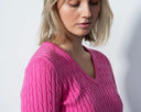 Woman wearing a pink sweater against a plain background