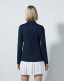 Person wearing a navy shirt and white pleated skirt against a light gray background