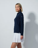 Woman wearing a navy shirt and white skirt against a gray background