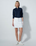 Woman wearing a navy shirt and white skirt on a plain background