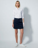 Woman wearing a white shirt and navy skirt on a plain background
