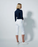 Person wearing a navy shirt and white pants against a plain background