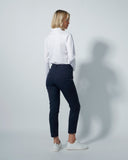 Person wearing a white shirt and navy pants against a plain background