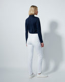 Person wearing a navy top and white pants against a plain background