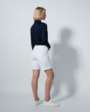 Person wearing a navy shirt and white shorts on a plain background