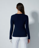 Person wearing a navy blue sweater and white pants against a gray background