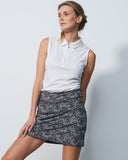 Woman wearing a white sleeveless top and patterned skirt against a light gray background