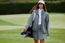 Woman walking on a golf course carrying golf clubs