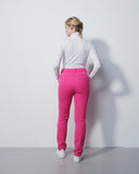 Person wearing a white shirt and pink pants against a white wall