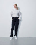 Person wearing a white turtleneck and black pants against a plain white background