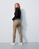 Woman wearing a black top and beige pants against a white wall