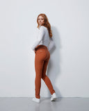 Woman wearing brown pants and a white top against a plain white background