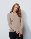 Woman wearing a beige sweater against a white background