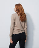 Woman wearing a beige jacket and black pants against a white background