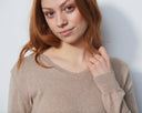 Woman wearing a beige sweater against a plain background
