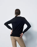 Person wearing a black long-sleeve shirt and beige pants against a white background