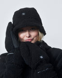 Person wearing a black winter outfit with a hat, coat, and gloves on a white background