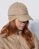 Person wearing a beige quilted cap and jacket against a white background