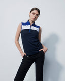 Woman wearing a sleeveless navy and white top with black pants on a light gray background