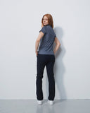 Woman wearing a patterned shirt and dark pants against a white background