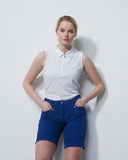 Woman wearing a white sleeveless shirt and blue shorts against a plain background