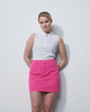 Woman wearing a white sleeveless top and pink skirt against a plain background