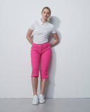 Woman wearing a white polo shirt and pink pants against a white background