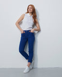 Woman wearing a white sleeveless top and blue jeans against a plain white background