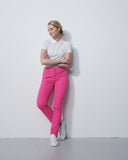 Woman wearing a white shirt and pink pants against a white background