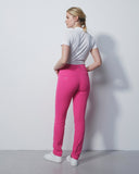 Woman wearing pink leggings and a white shirt against a plain background