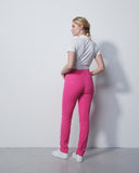 Woman wearing pink leggings and a white shirt against a plain background