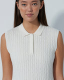 Woman wearing a white sleeveless ribbed top against a plain background