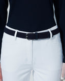 Person wearing a navy top and white pants with a navy belt on a plain background