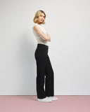 Woman wearing a sleeveless top and black pants against a plain background