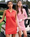 Two girls wearing red leaning against a golf cart.