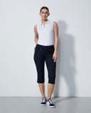 Woman wearing a white sleeveless shirt and black capri pants against a plain background