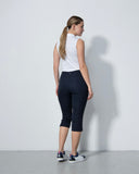 Woman wearing a white sleeveless top and black capri pants against a plain white background