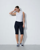 Woman wearing a white polo shirt and black shorts against a white background