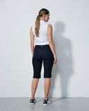 Woman wearing a white sleeveless top and black capri pants against a plain background